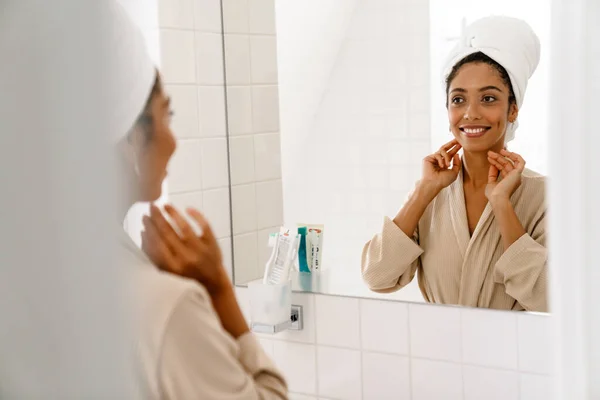 Afrykańska Młoda Kobieta Ręcznikiem Głowie Uśmiechnięta Patrząca Lustro Łazience — Zdjęcie stockowe