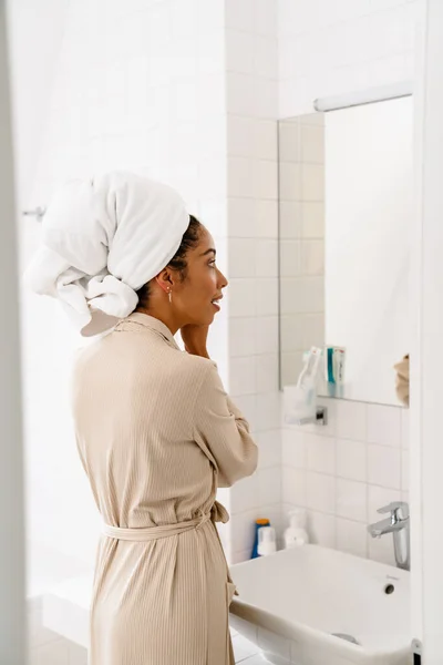 Mujer Joven Afroamericana Con Toalla Cabeza Sonriendo Llevando Pendientes Baño — Foto de Stock