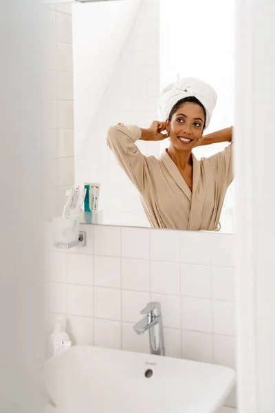 Mujer Joven Afroamericana Con Toalla Cabeza Sonriendo Mirando Espejo Baño — Foto de Stock
