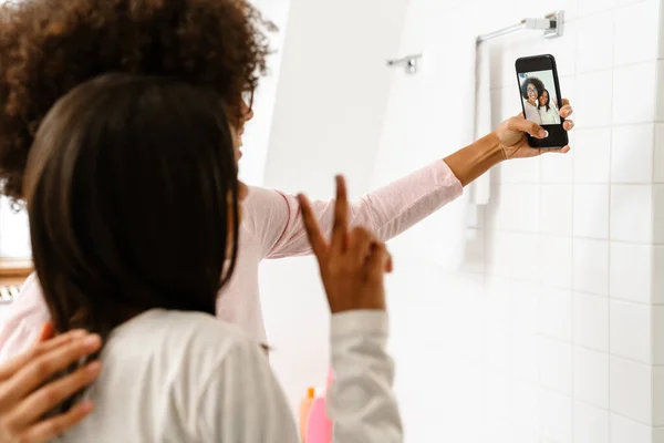 Musta Tyttö Hänen Äitinsä Elehtivät Ottaessaan Selfie Kännykkään Kylpyhuoneessa Kotona — kuvapankkivalokuva