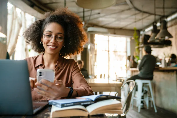 Mujer Afroamericana Joven Usando Teléfono Celular Mientras Trabaja Por Mesa —  Fotos de Stock
