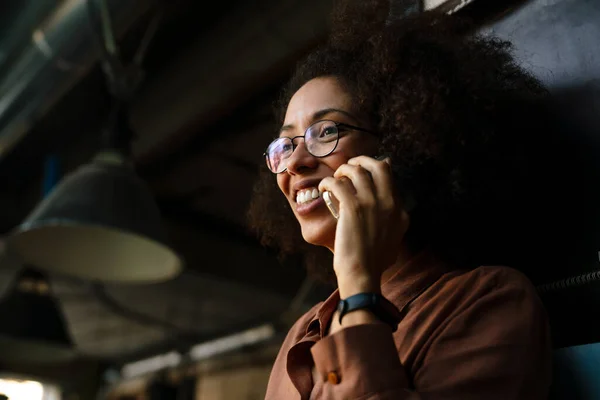 年轻的非洲裔美国女人一边在咖啡店用手机聊天 一边笑着 — 图库照片