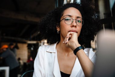 Genç Afro-Amerikalı kadın kafeteryada otururken dizüstü bilgisayar kullanıyor.