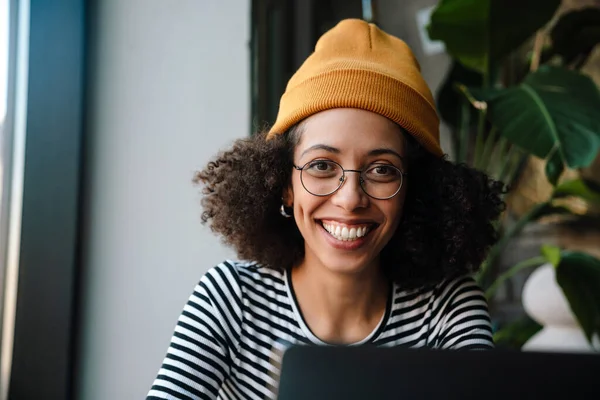 Joven Mujer Afroamericana Sonriendo Utilizando Ordenador Portátil Mientras Está Sentado —  Fotos de Stock
