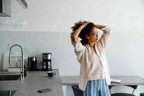 Black Woman Wearing Eyeglasses Holding Her Hair While Standing Kitchen — Stock Photo, Image