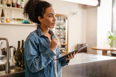 Kapalı bir kafede çalışan siyah barista kadın notlar yazıyor.