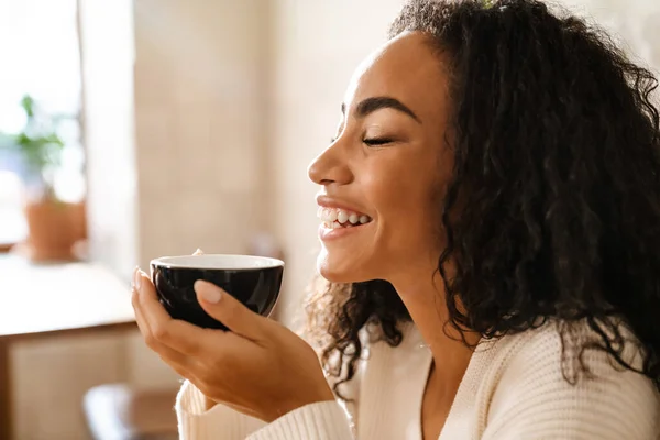 Młoda Czarna Kobieta Śmieje Się Pije Kawę Siedząc Kawiarni — Zdjęcie stockowe