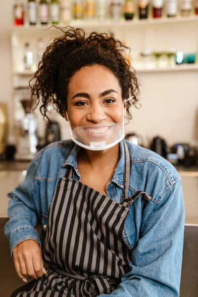 Joven Camarera Negra Con Delantal Mascarilla Sonriendo Mientras Trabaja Cafetería —  Fotos de Stock