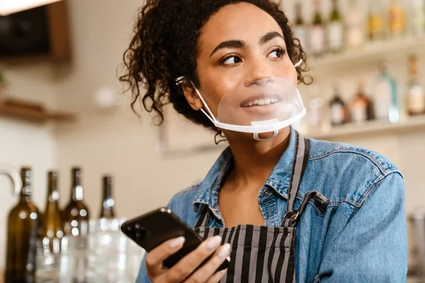 Kapalı Kafede Çalışırken Cep Telefonu Kullanan Yüz Maskeli Genç Zenci — Stok fotoğraf