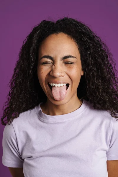 Genç Siyah Kadın Dalgalı Saçlı Dilini Mor Arka Planda Soyutlamış — Stok fotoğraf