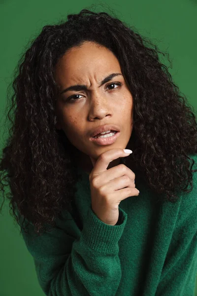 年轻的黑人女人皱着眉头看着被绿色背景隔离的相机 — 图库照片