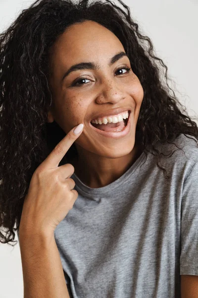 Молода Чорна Жінка Хвилястим Волоссям Вказує Пальцем Посмішку Ізольовано Білому — стокове фото