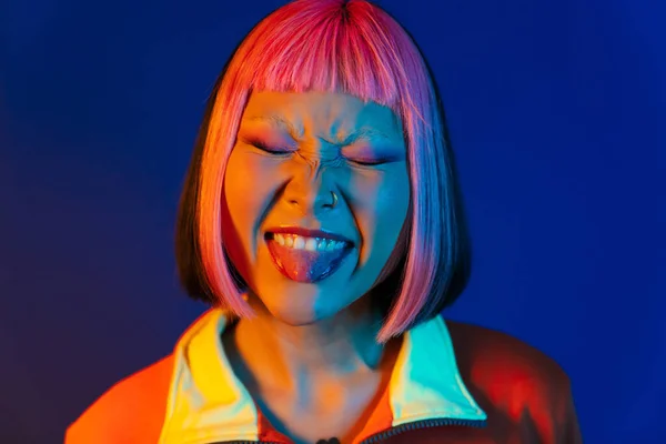 Azji Dziewczyna Różowymi Włosami Przekłuwanie Pokazując Jej Język Izolowane Niebieskim — Zdjęcie stockowe