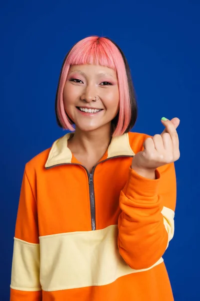 Mavi Arka Planda Parmaklarını Sürterek Gülen Pembe Saçlı Asyalı Kız — Stok fotoğraf