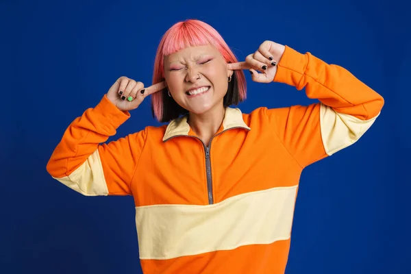 Azjatycka Dziewczyna Różowymi Włosami Marszczy Brwi Zatyka Uszy Izolowane Niebieskim — Zdjęcie stockowe