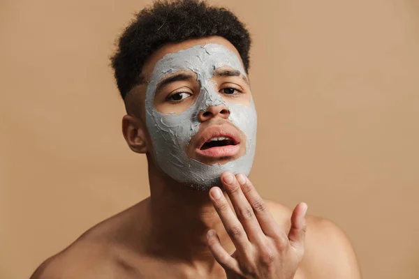 Çene Kemiğine Dokunan Kozmetik Kilden Maskeli Genç Üstsüz Adam Bej — Stok fotoğraf