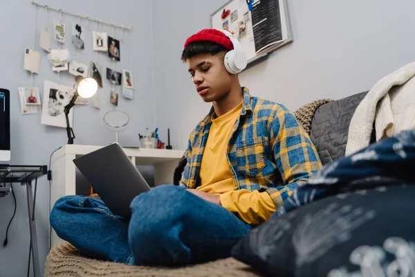 Middle Eastern Teenage Boy Headphones Using Laptop While Sitting Couch — Stock Photo, Image