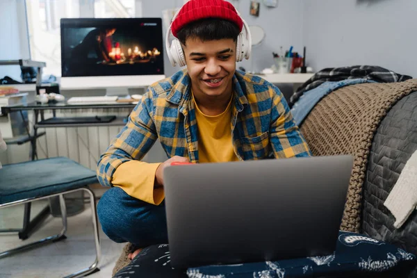 Middle Eastern Teenage Boy Using Laptop Cellphone While Sitting Couch — Stock Photo, Image