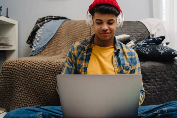 Adolescente Oriente Medio Usando Portátil Auriculares Mientras Está Sentado Suelo —  Fotos de Stock