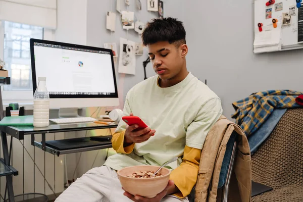 Brunette Teenage Boy Using Cellphone Eating Breakfast Bedroom — Stock Photo, Image