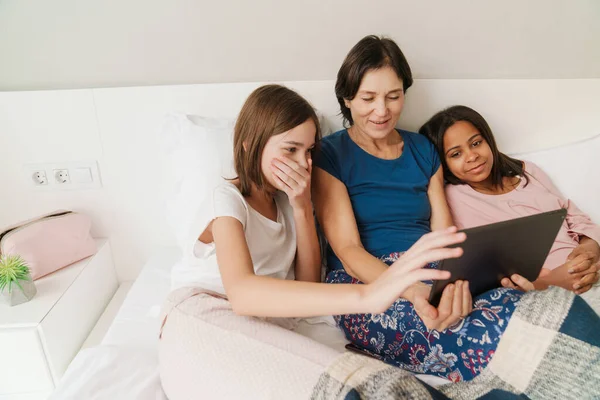 白人妇女和她的女儿在床上休息时使用平板电脑 — 图库照片