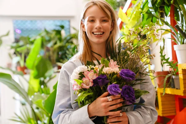 漂亮的年轻卖花的白人姑娘手里拿着鲜花在商店里 — 图库照片