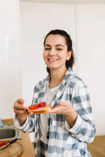 stock image Young woman smiling and making sandwich in kitchen at home