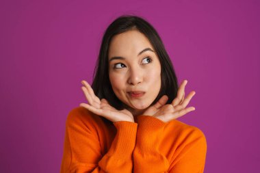 Genç Asyalı kadın somurtuyor ve kopyalama alanını mor arka planda izole ediyor