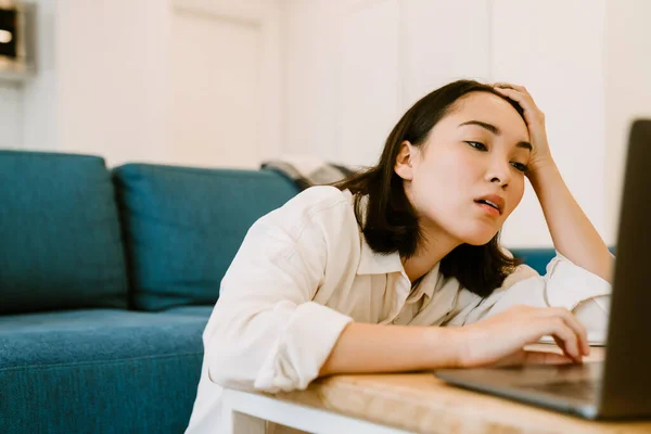 Młody Zmęczony Azji Kobieta Laptopem Patrząc Ekranie Przytulny Salon Domu — Zdjęcie stockowe