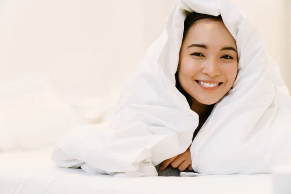 Joven Sonriente Asiático Chica Casa Traje Acostado Cama Bajo Cubiertas —  Fotos de Stock