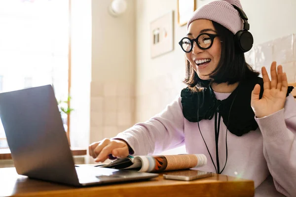 Young Asian Woman Headphones Gesturing Using Laptop Cafe —  Fotos de Stock