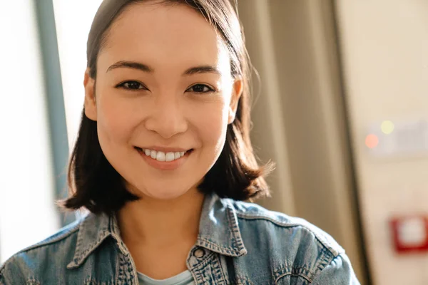 年轻的亚洲女人 穿着斜纹棉布衬衫 面带微笑 看着屋里的相机 — 图库照片