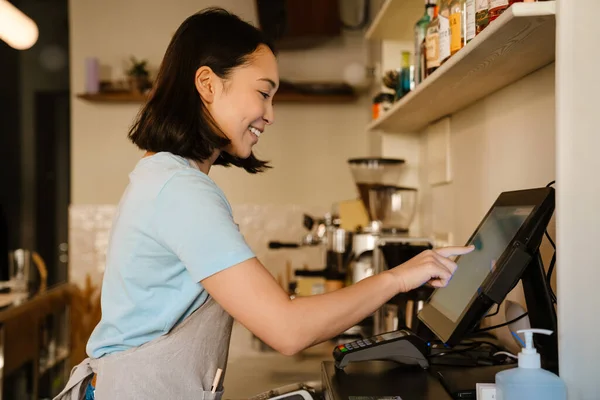 Kafede Yazar Kasada Çalışırken Önlük Takan Asyalı Kadın Gülümsüyor — Stok fotoğraf