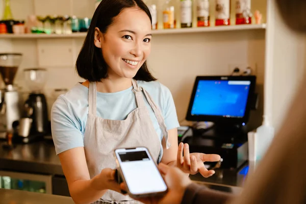 カフェでクライアントと仕事をしながら エプロン笑顔を身に着けているアジアのバリスタ女性 — ストック写真