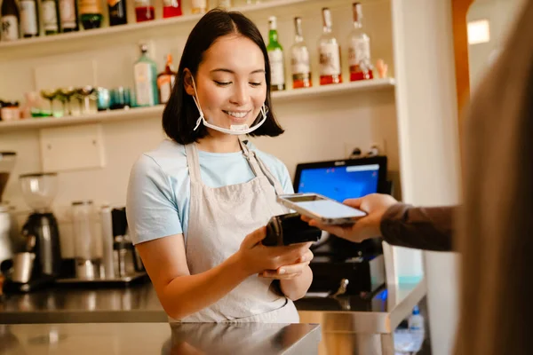 Kahve Maskesindeki Asyalı Kadın Müşteriyle Çalışırken Gülümsüyor — Stok fotoğraf