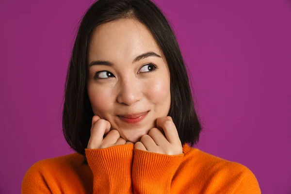 年轻的亚洲女人 穿着毛衣 面带微笑 与紫色背景隔离 望着旁边 — 图库照片