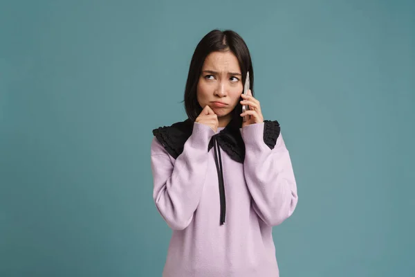 Νεαρή Ασιάτισσα Που Κατσουφιάζει Και Μιλάει Στο Κινητό Τηλέφωνο Απομονωμένη — Φωτογραφία Αρχείου
