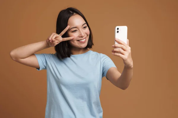 Молодая Азиатская Женщина Жестикулирует Делая Селфи Мобильном Телефоне Изолированы Бежевом — стоковое фото