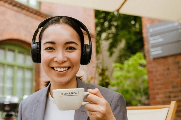 Asiatisk Kvinna Hörlurar Lyssnar Musik Medan Dricker Kaffe Café Utomhus — Stockfoto