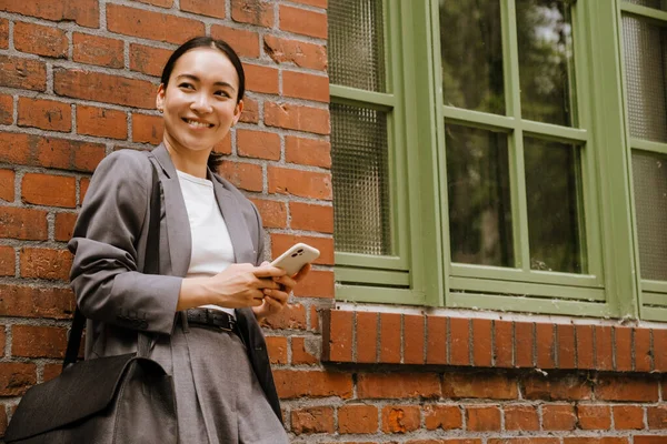 Asiatisk Ung Affärskvinna Som Använder Mobiltelefon Stående Vid Väggen Utomhus — Stockfoto