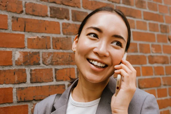 Asiático Jovem Empresária Sorrindo Falando Celular Enquanto Parede Rua — Fotografia de Stock