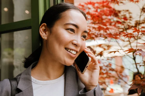 Asiática Joven Mujer Negocios Sonriendo Hablando Teléfono Celular Mientras Que —  Fotos de Stock