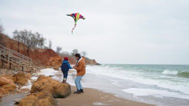 Gülümseyen baba ve oğul sahilde uçurtma uçuruyorlar.
