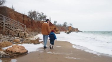 Yakışıklı baba ve oğul deniz kenarında konuşuyor ve yürüyor.