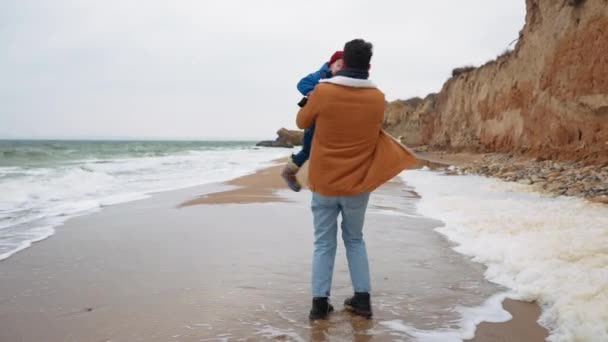 Uśmiechnięty Ojciec Kręci Synem Ramionach Plaży Nad Morzem — Wideo stockowe