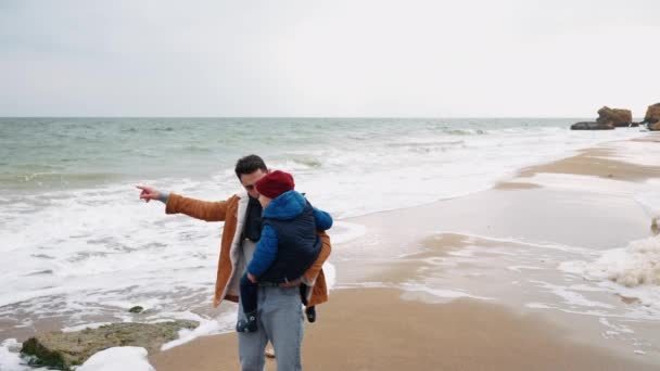 Poważny Ojciec Trzymający Syna Ramionach Mówiący Blisko Morza — Wideo stockowe