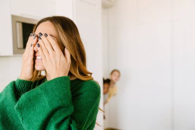 Anne, kızlarıyla saklambaç oynarken elleriyle gözlerini kapatıyor. Evlat edinme kavramı