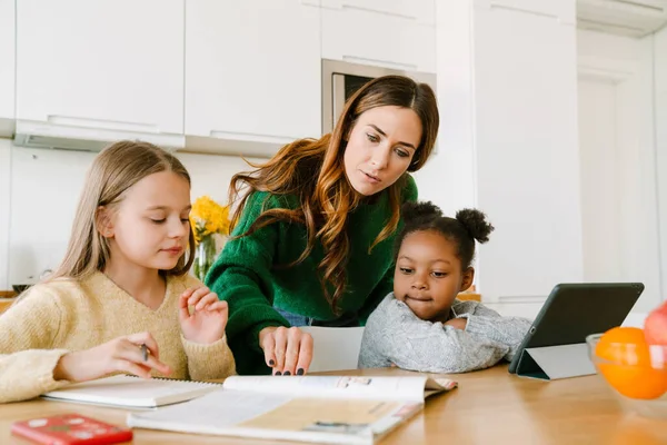 Konzentrierte Mutter Hilft Ihren Töchtern Bei Den Hausaufgaben Der Gemütlichen — Stockfoto