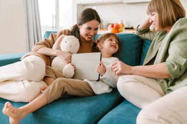 Beyaz kız ailesiyle evde vakit geçirirken tablet bilgisayar kullanıyor.