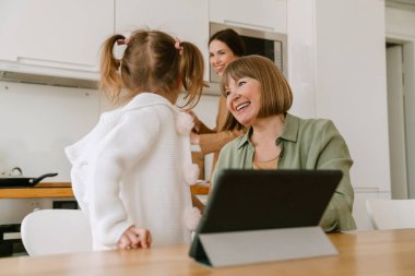 Beyaz kız ailesiyle evde vakit geçirirken tablet bilgisayar kullanıyor.